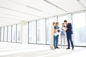 Full length of business people reviewing documents in new office