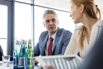 Mature businessman discussing with female colleague in board room