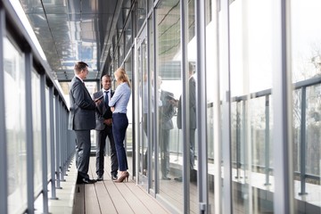 Full length of multi-ethnic business people discussing on office balcony