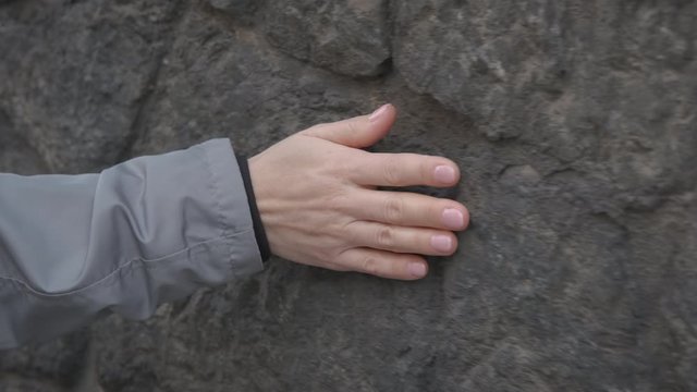 Hand on stone wall. Woman's hand on an old stone wall.