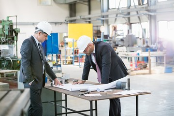 Businessmen examining blueprint at workbench in metal industry