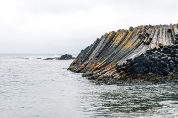 Closeup shot of rocky basalt volcanic textured columns in Kalfshamarsvik in Iceland during heavy...