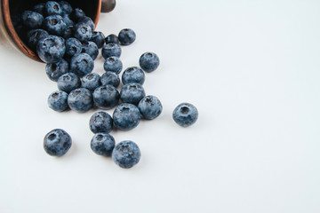  A bunch of ripe blueberries on a white background copy space. Blueberries spilling out of a stein.