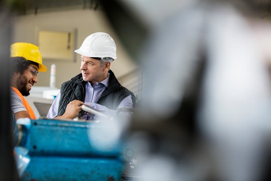 Mature Male Supervisor Talking With Worker In Metal Industry