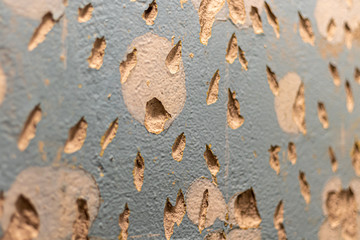 Tiled wall. Preparation for repair. Broken and gritty surface. Rough texture of blue color with brown spots.