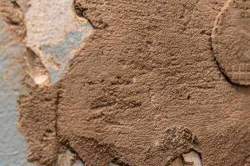 Tiled wall. Preparation for repair. Broken and gritty surface. Rough texture of blue color with brown spots.