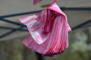 Group of pink plastic bags blowing in the wind, in display at a food market