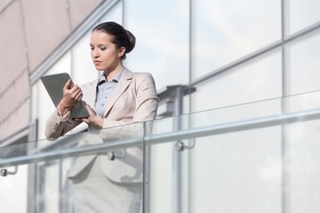 Beautiful young businesswoman using digital tablet at office railing