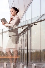 Beautiful young businesswoman using digital tablet at office railing