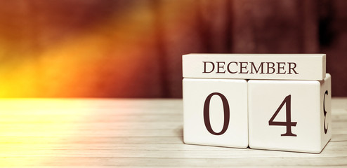 Calendar reminder event concept. Wooden cubes with numbers and month on December 4 with sunlight.