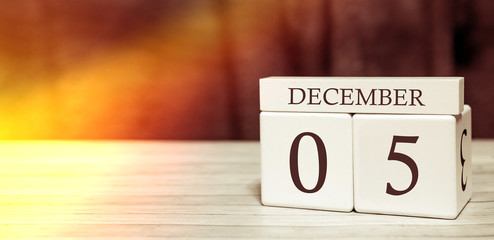 Calendar reminder event concept. Wooden cubes with numbers and month on December 5 with sunlight.