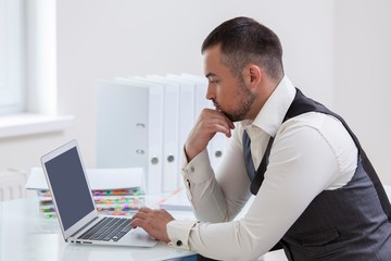 Young businessman using at laptop at desk