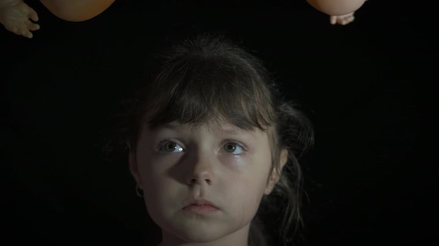 Horror with toys. Child's fear. A frightened little girl is afraid of dolls.
