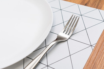 White plate and stainless steel fork at the dining table