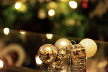 Christmas balls and present decorations with colorful tree in background