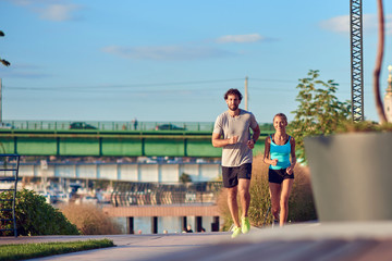 Modern woman and man jogging / exercising in urban surroundings near the river.