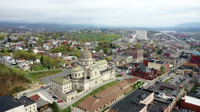 Aerial drone flying over small, rural downtown of Altoona Pennsylvania in the summer showcasing the buildings and large church
