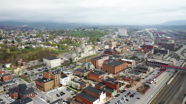Aerial drone flying over small, rural downtown of Altoona Pennsylvania in the summer showcasing the railroad and large church