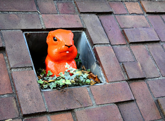 Orange plastic prairie dog head and shoulder view in a brick wall