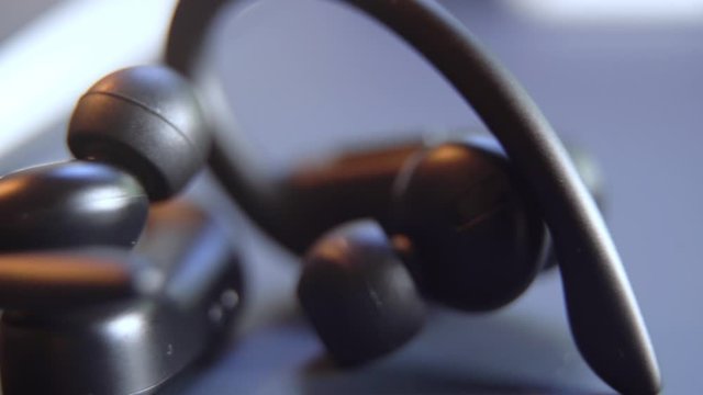 close up at black wireless earphones on the table ,technology concept 