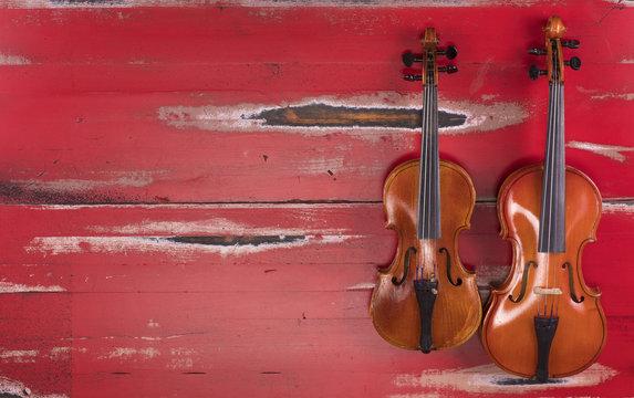 two violins on a red wooden background