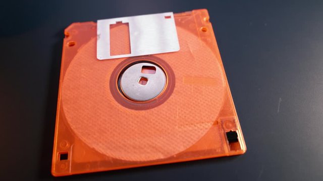 orange Floppy disk on the table , old type of data storage , Retro floppy disk sitting on the desktop , 