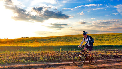 Fototapeta na wymiar cyclist rides a bicycle on a track at sunset