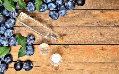 Top view to shots of Slivovice and bottle on rustic wooden table - plum brandy, typical spirit from Eastern Europe.