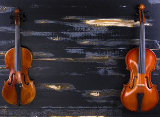 two violins on a black wooden background
