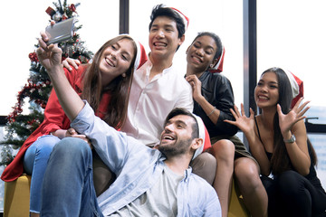 Celebrating New Year together, group of beautiful young people in Santa hats having fun.