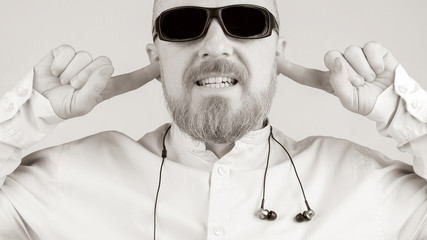 Bearded man with fingers in his ears instead of headphones