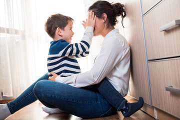 Beautiful mom and her son on the floor being affectionate with each other.