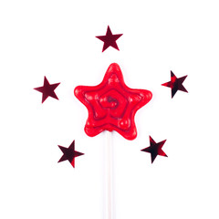 Red star shaped lollipop on white background with five stars confetti.