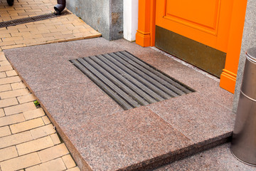 threshold of an orange wooden entrance door with foot mat close up side view.