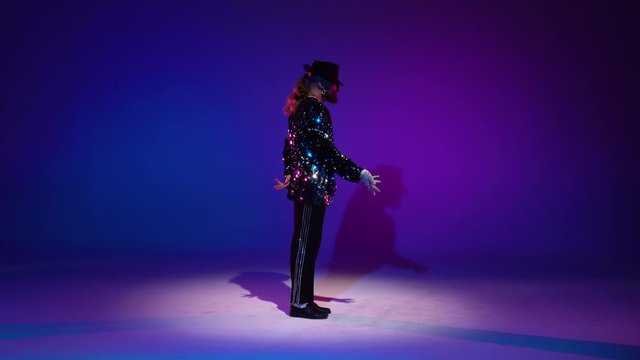 Young stylish man dancing, spotlight on a blue background.