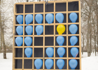 Colored balloons on a wooden bench. The game is throwing darts into balls, entertainment in the park for adults and children.