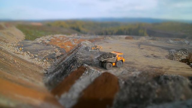 A huge yellow dump truck unloads stones from the body. Wide-angle tilt-shift panorama Coal mining at the quarry 