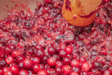 Crush the red cranberry berries with a wooden rolling pin