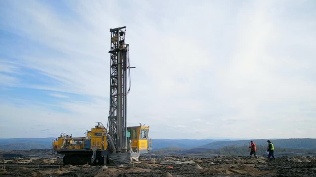 Panorama two workers go to the drilling machine. Preparing a quarry for coal mining
