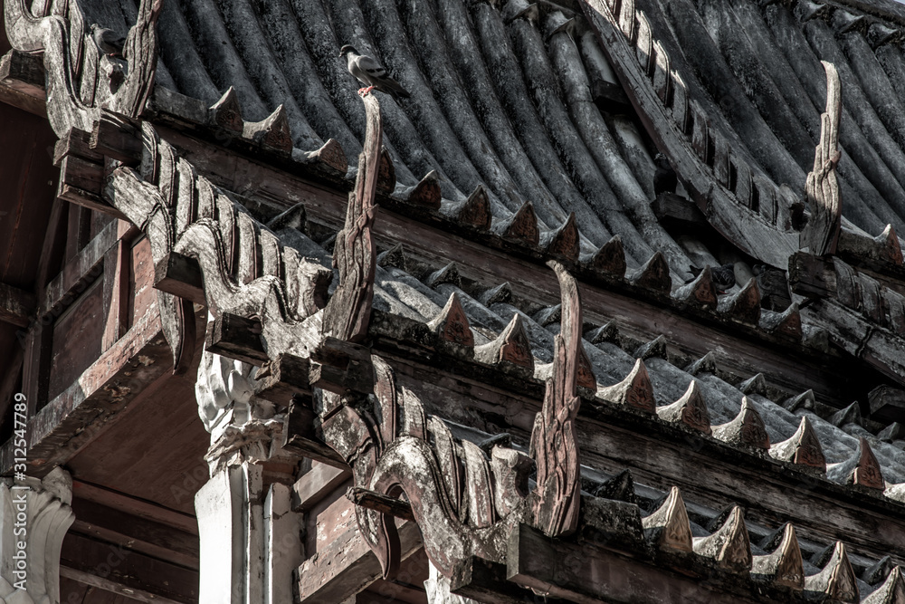 Wall mural A pigeons perched on the Old wooden roof at chapel at chong Nonsi buddhist temple (Wat Chongnonsi) in rama3 road.