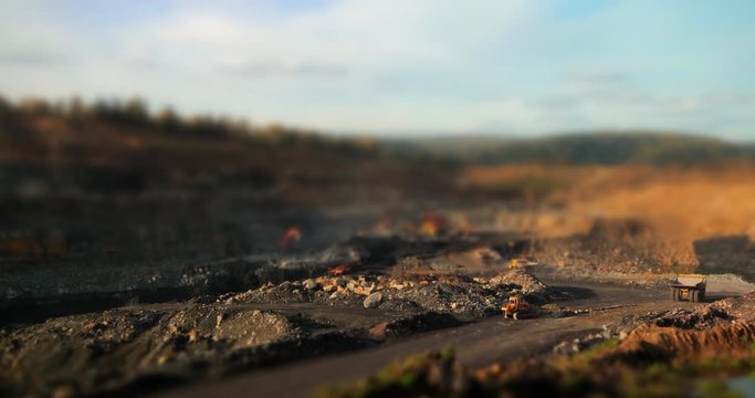 Timelapse tilt-shift panorama of coal mining quarries, red excavators dig coal and load into yellow dump trucks