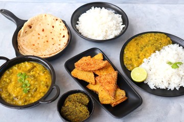 Assorted Indian food for lunch or dinner, rice, spinach lentils/Palak dal, Roti or naan, Alu Vadi and surnache kap / Yam fry. selective focus with Copy space