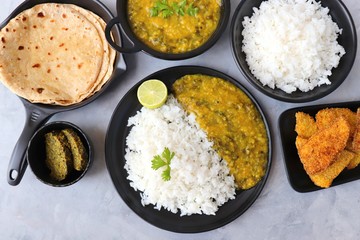 Assorted Indian food for lunch or dinner, rice, spinach lentils/Palak dal, Roti or naan, Alu Vadi and surnache kap / Yam fry. selective focus with Copy space