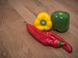 Various raw peppers on wooden surface