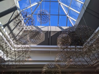 Giant festive chandeliers in a mall below a sun roof.