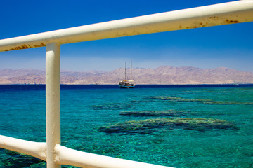 summer time cruise vacation trip touristic agency pattern concept of liner on Red sea waters in Gulf of Aqaba Middle East district, white fence frame work foreground