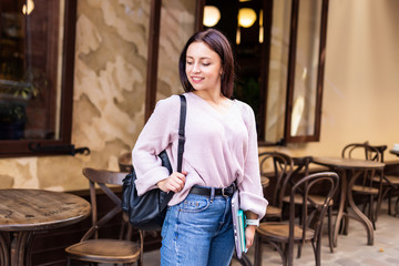 Happy student woman holding folders walking on the street