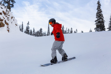 Male Snowboarder is riding down a ski run in wintertime. Taken on Whistler Mountain, British...