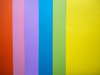 Different colors paper top view abstract background. Orange, pink, purple, blue, green and yellow cardboard paper sheets.