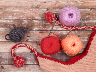 Balls of threads for knitting, knitting needles, knitted mouse and wool hat on wooden background